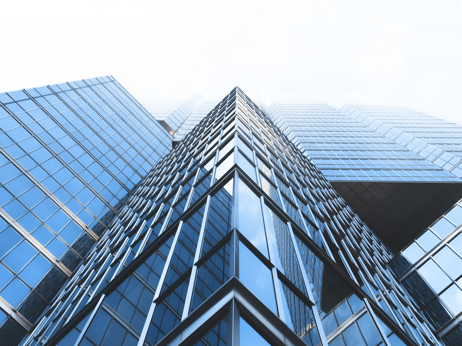 Upward view of modern glass office towers converging against the sky